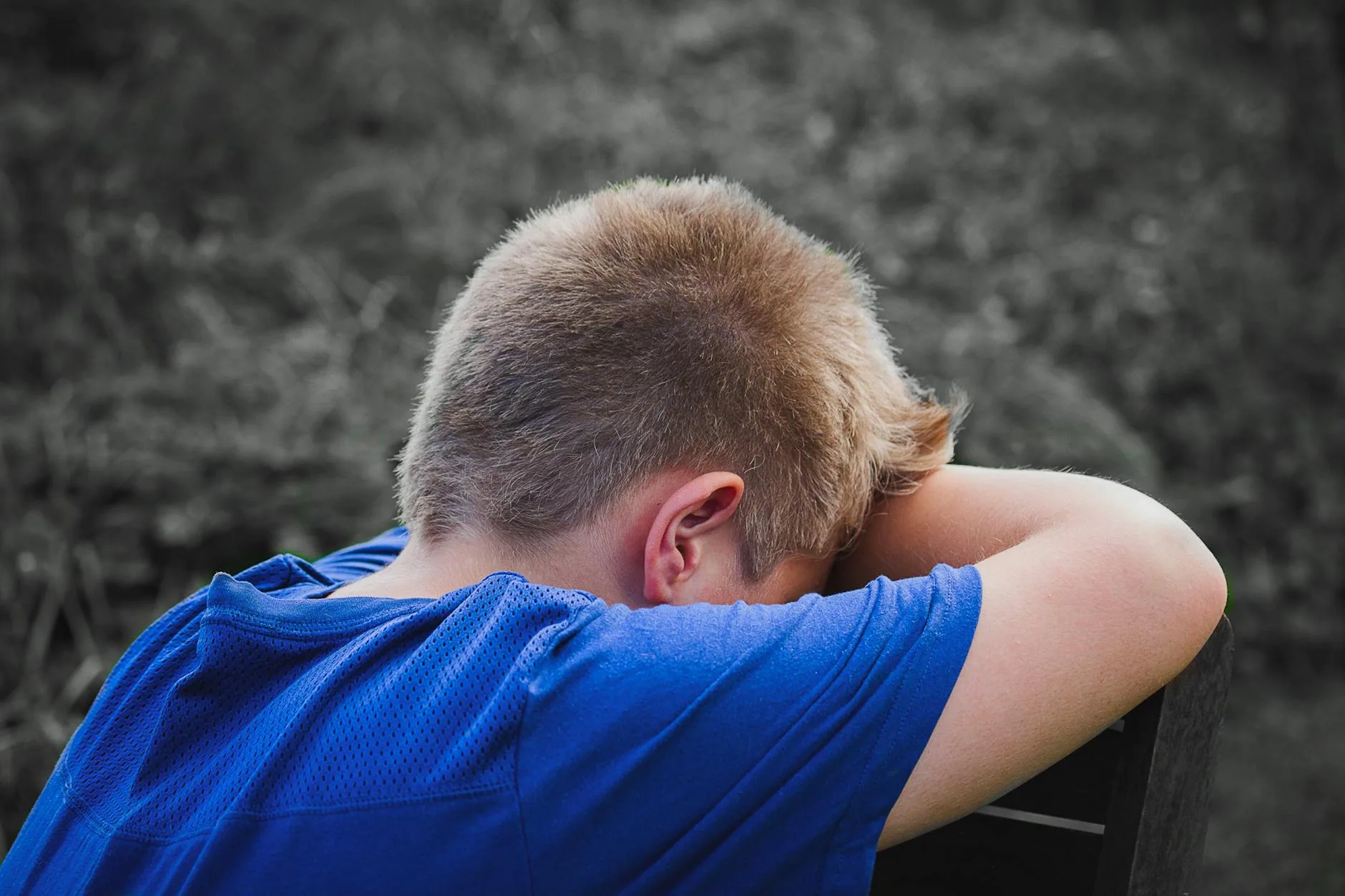 Pies z lękiem separacyjnym: czy da się to przewidzieć przy wyborze? Smutny chłopiec w niebieskiej koszulce siedzi na dworze z głową na rękach
