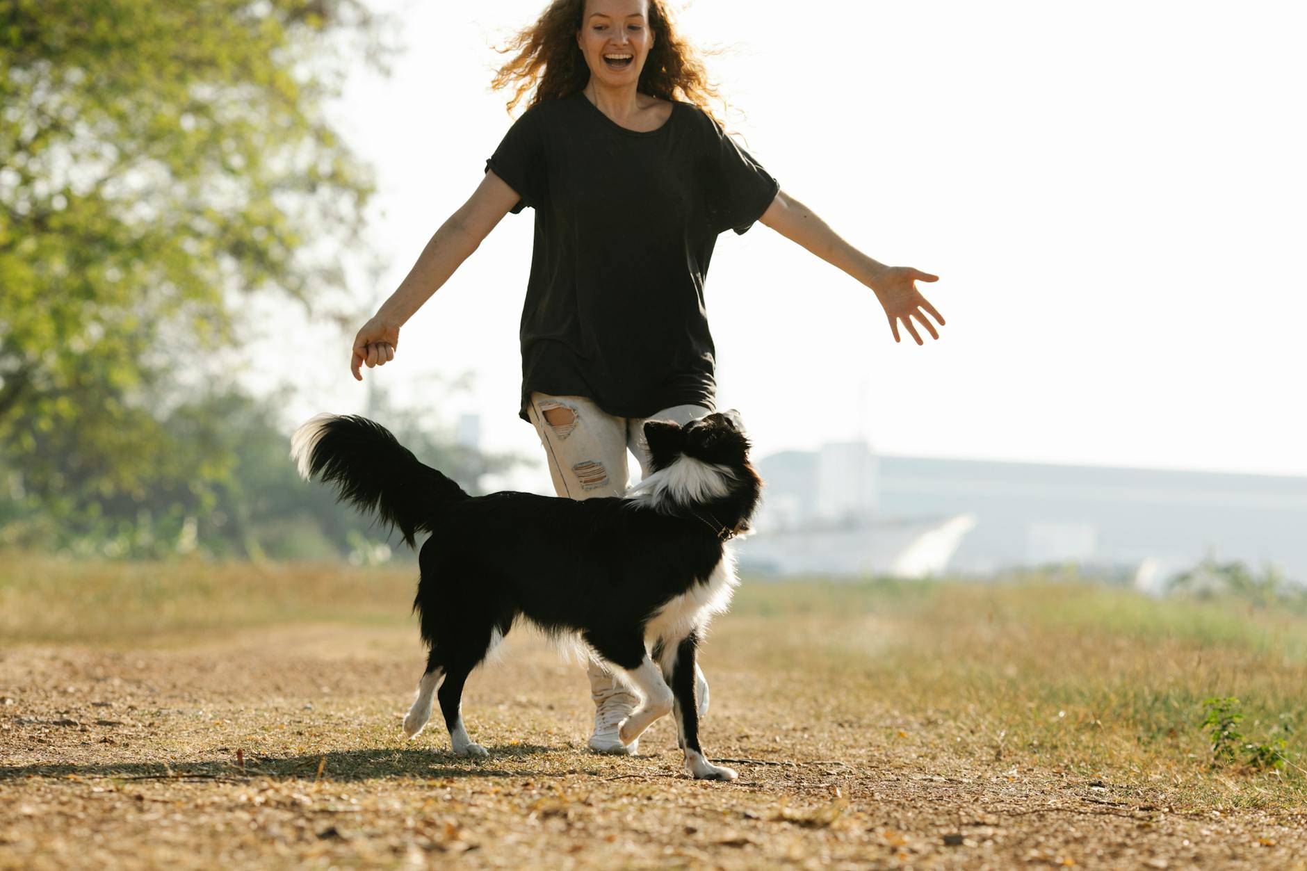 Kobieta biegnąca z czarnym border collie po wiejskiej ścieżce