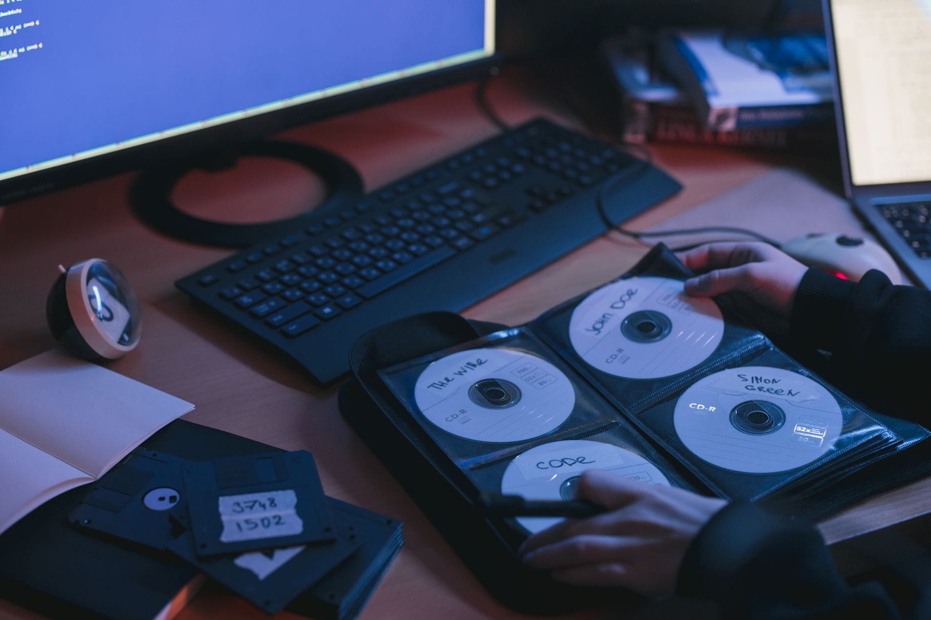 Płyty CD i dyski na biurku w technicznym otoczeniu dłoni
